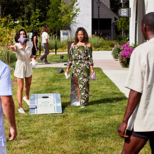 Settle into comfort at NOVEL Ballantyne a group of people playing cornhole